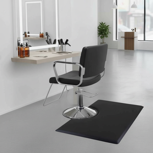 Black salon chair in a modern salon setting with mirrors and products and a Rectangular 1" Anti-Fatigue Beauty Salon Floor Mat